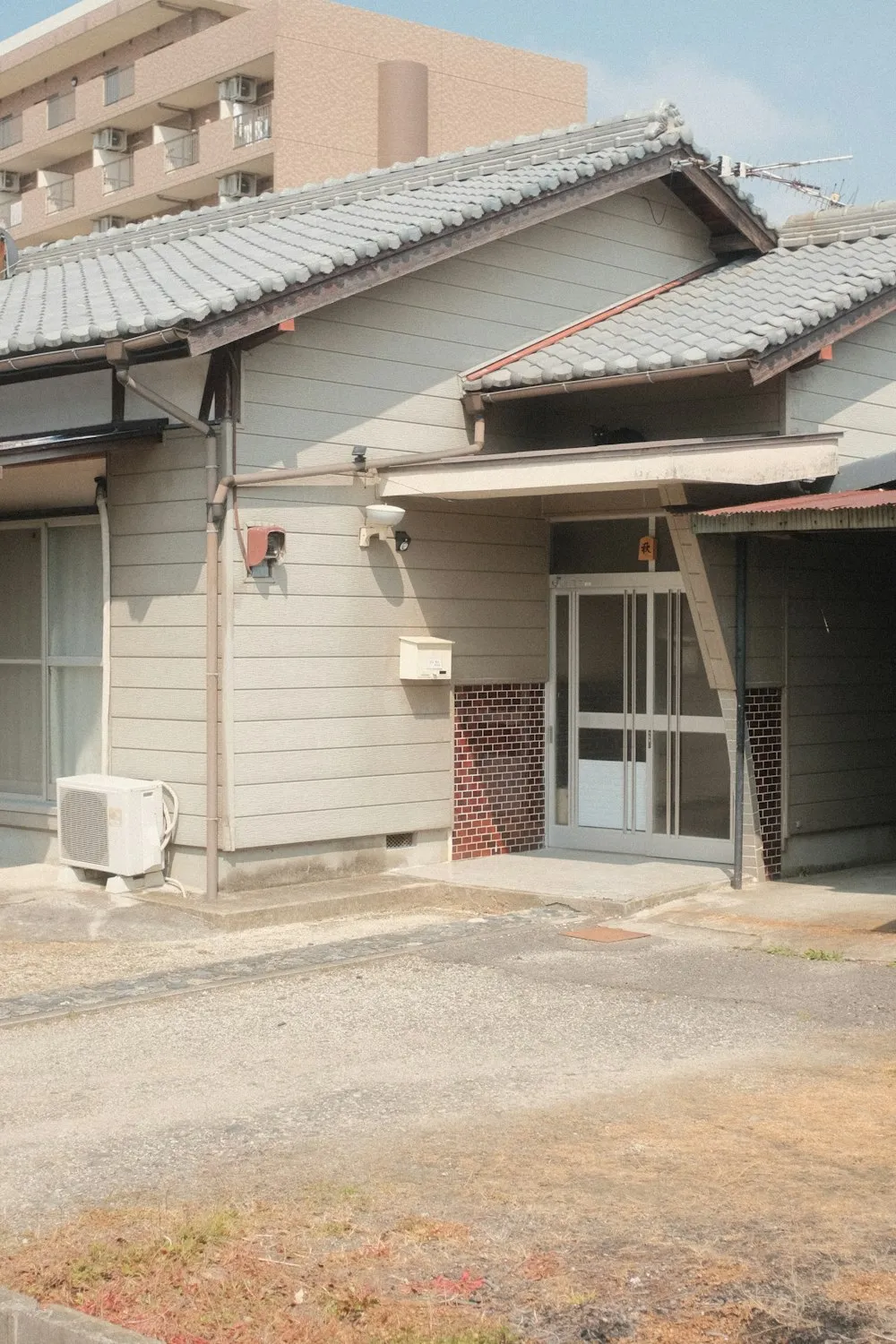 white plastic trash bin beside brown brick house