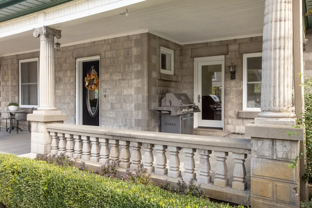 a front porch with columns and a grill